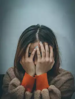 Frau erschöpft mit Händen vor dem Gesicht